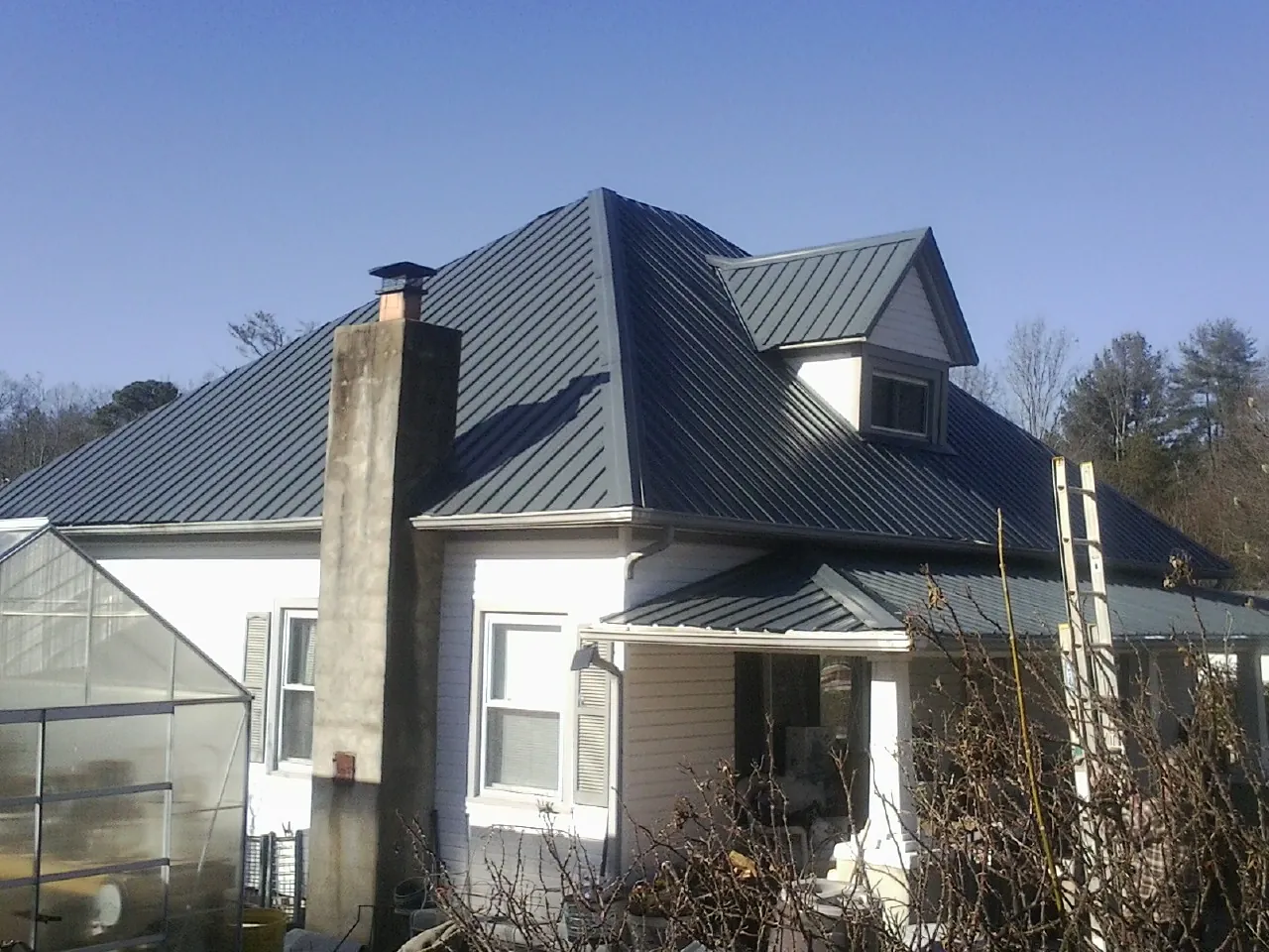 Dark blue standing seam metal roof on a white farmhouse with dormer — Slate & Tile Roof Repair by Roofing Brothers in Mackville