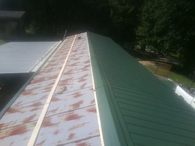 Old rusted panels beside newly installed green metal roofing — Wind Damage Roof Repair by Roofing Brothers in Mackville