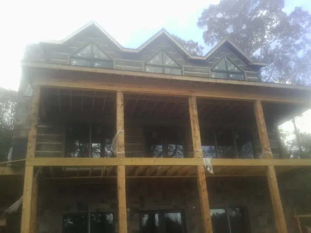 Dormers and porch framing on a large log home under construction — Roof Coating work by our crew in Mackville