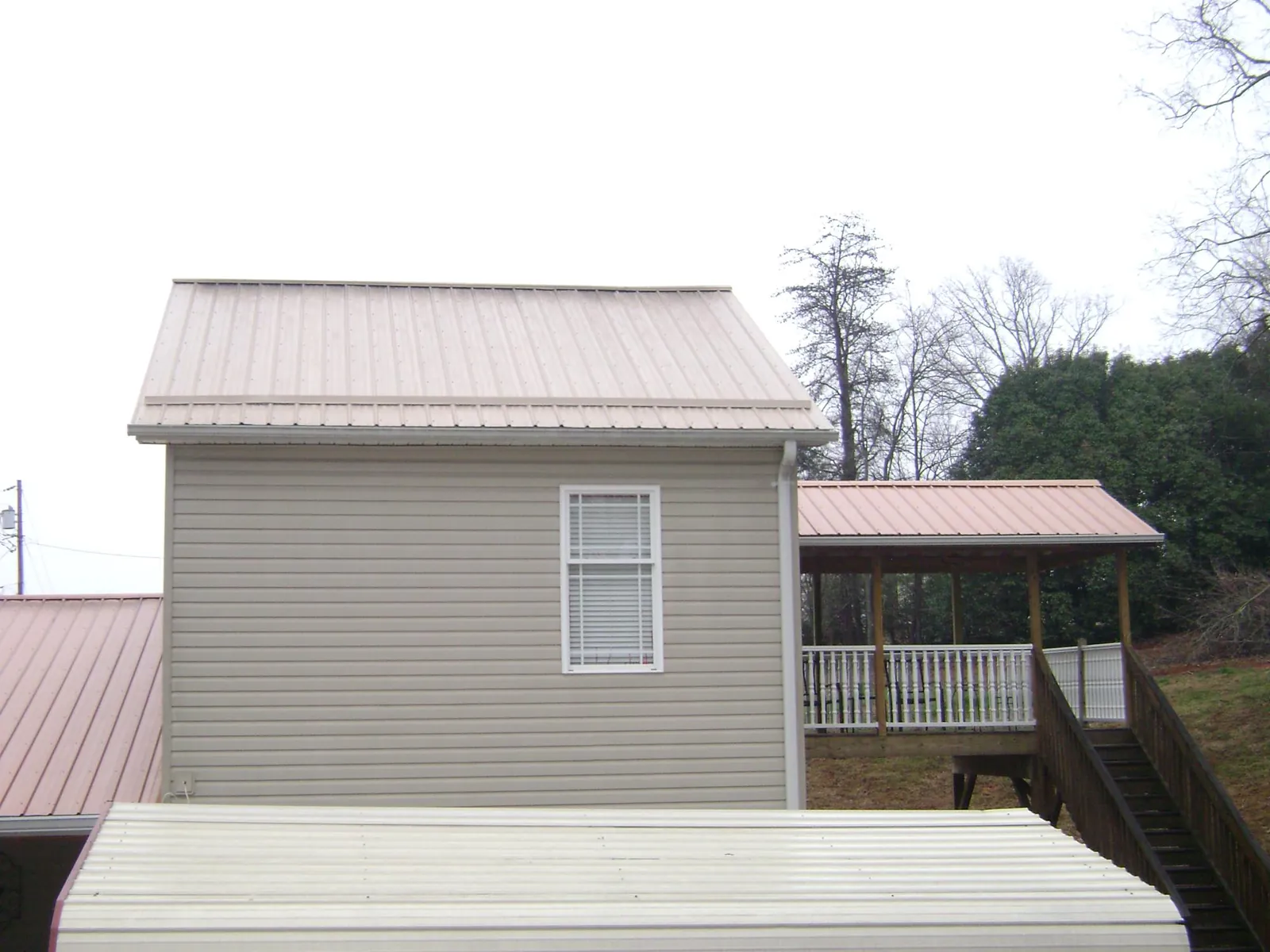 Tan metal roofs on a two story addition and attached porch, from a Roof Replacement job in Mackville